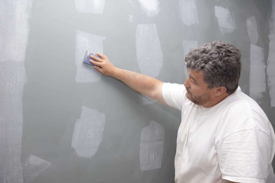 A contractor sanding a drywall patch